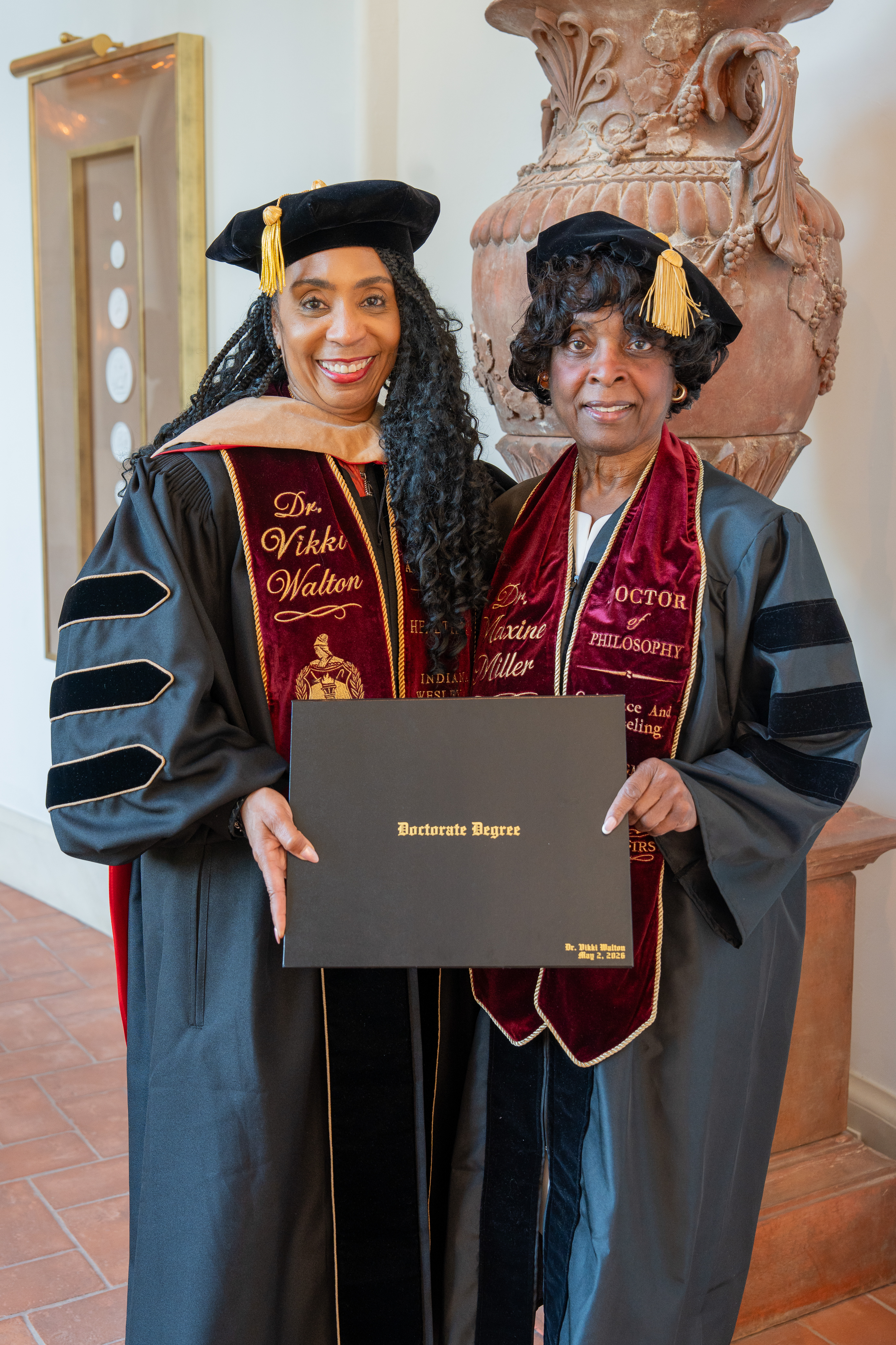 Two women laughing together looking at a phone at a graduation celebration