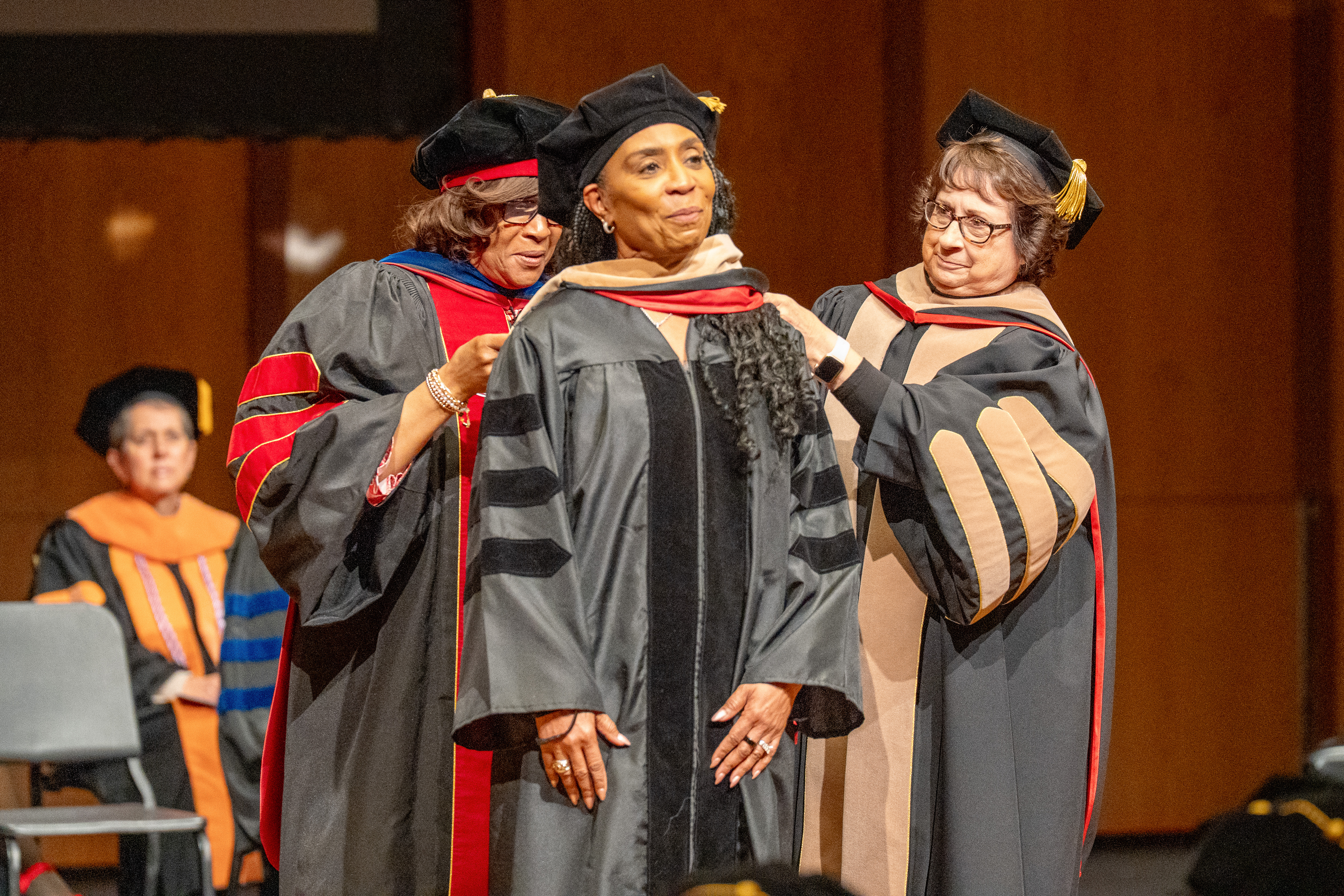 Graduate celebrating outdoors on a campus bench in her doctoral regalia