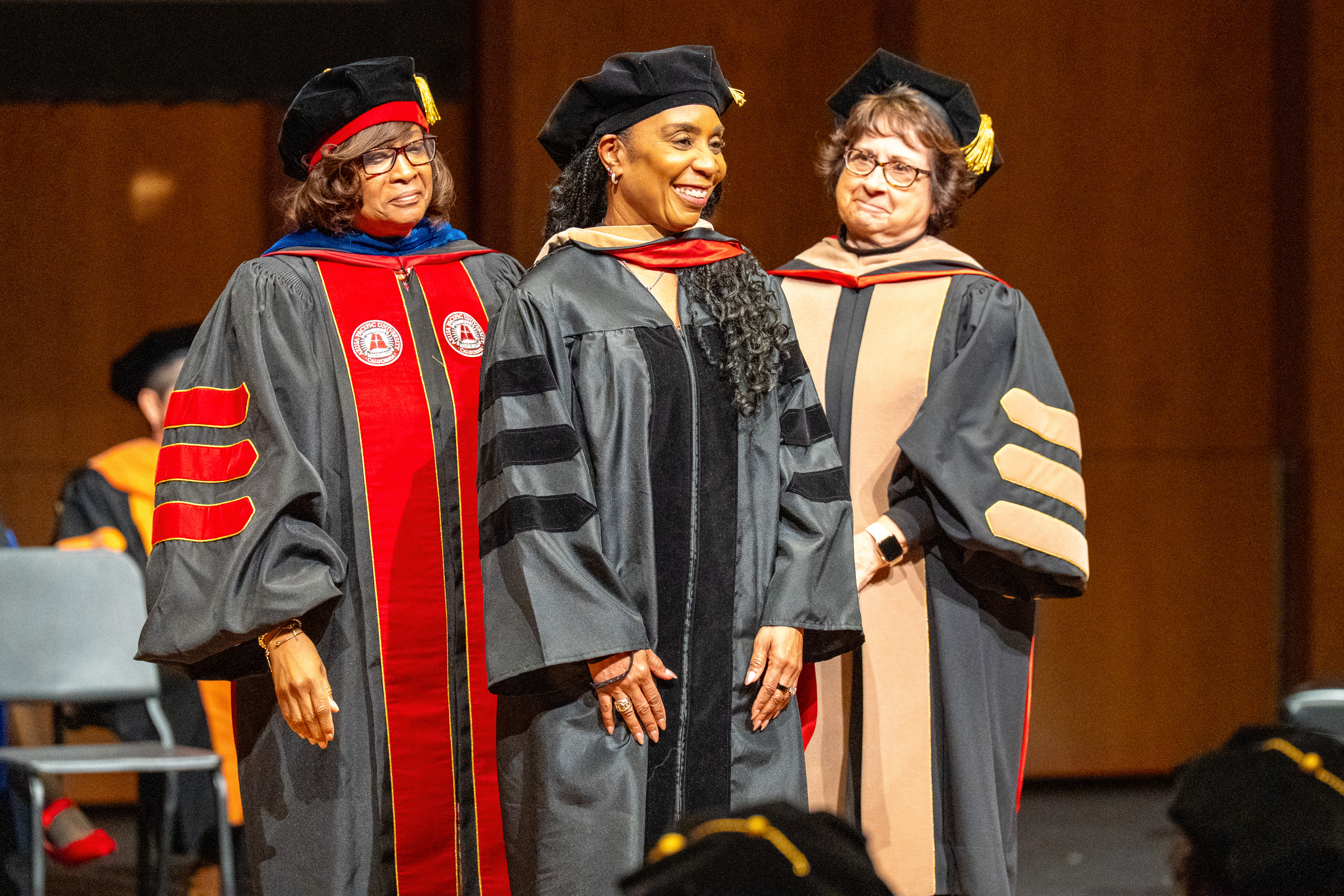 Two graduates shaking hands on stage at a commencement ceremony