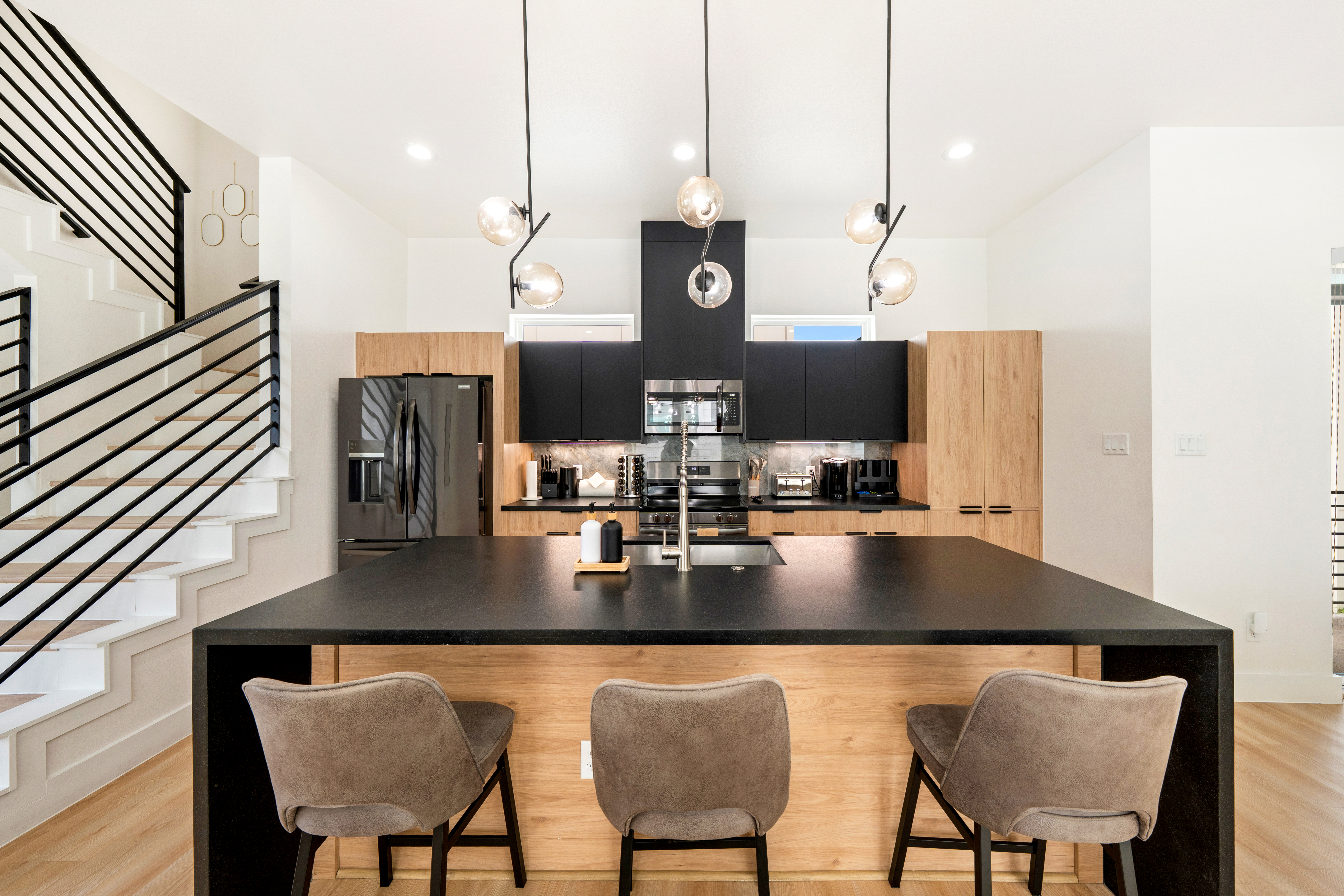 Kitchen with black island and modern pendant lighting