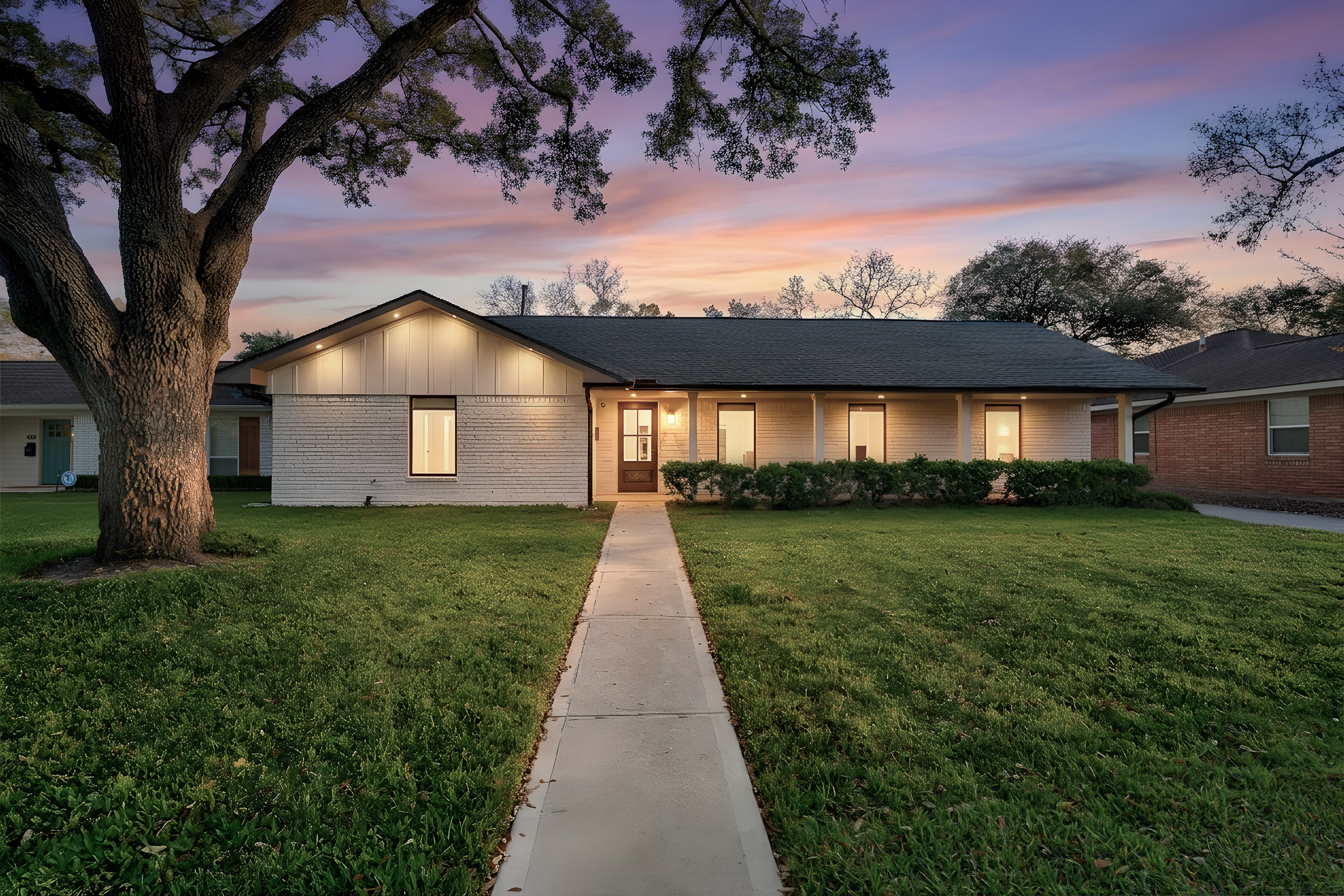 Twilight exterior of a two-story brick home with landscaped walkway