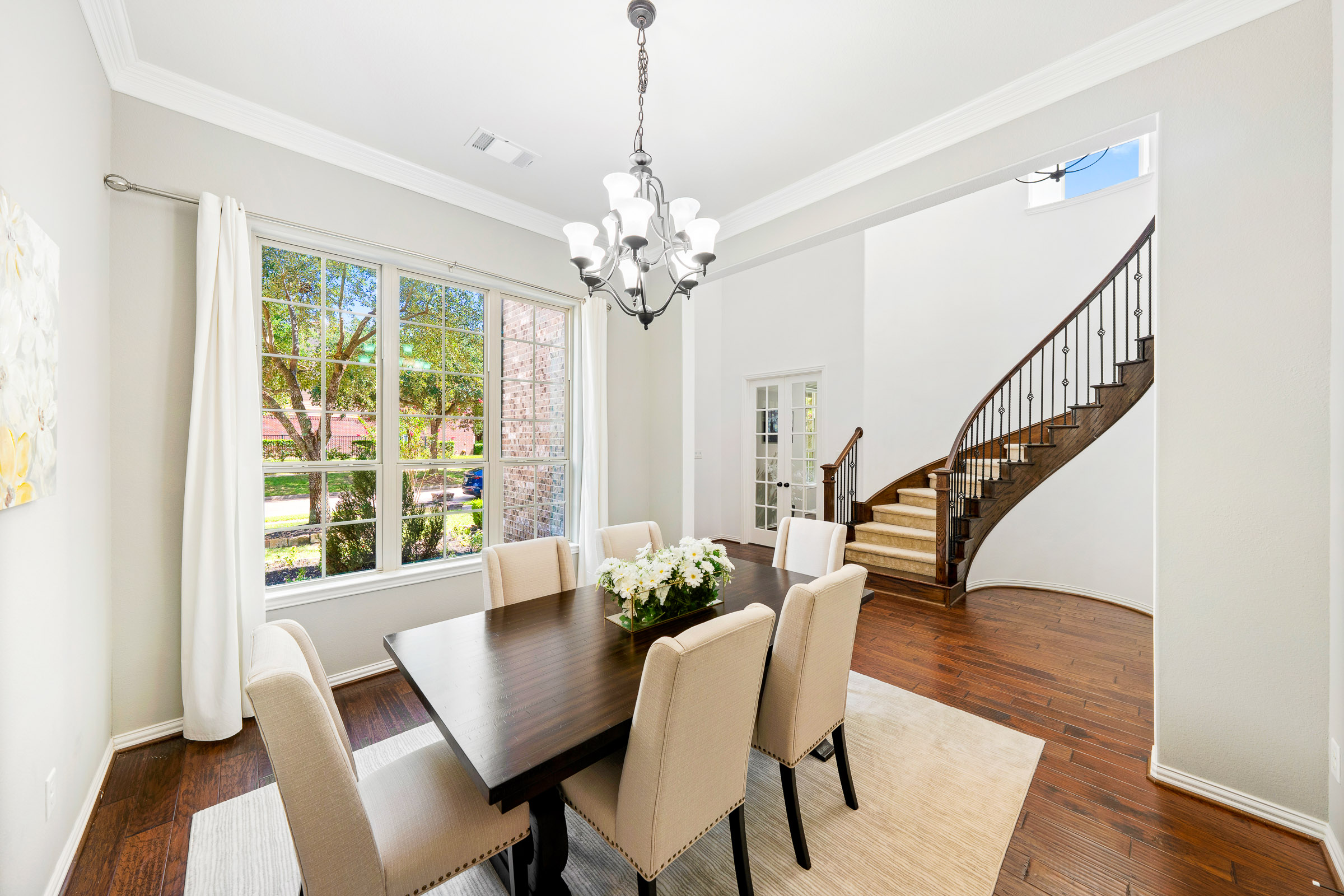 Formal dining room with curved staircase and tall windows