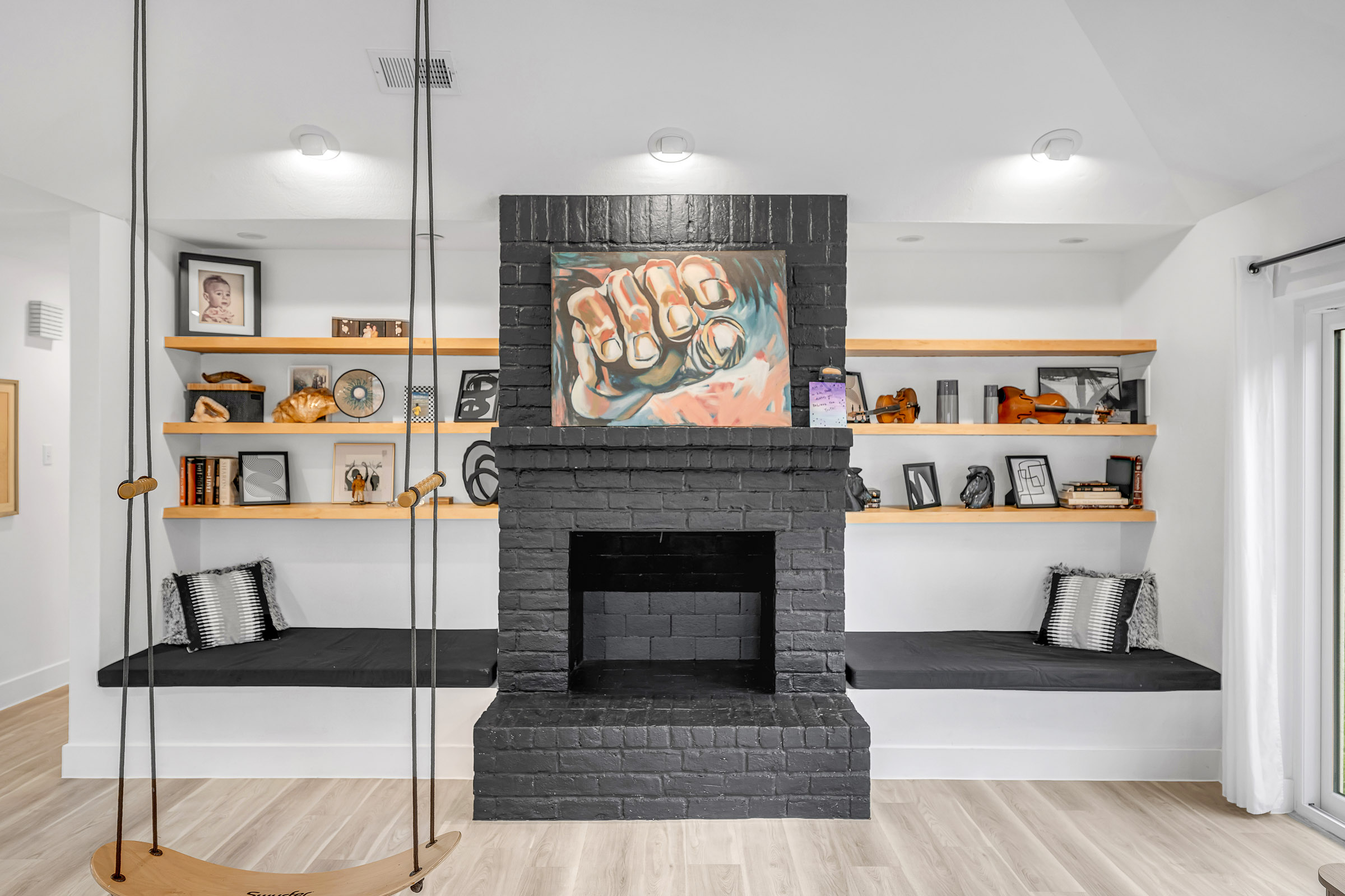 Living room with black brick fireplace, floating shelves and built-in benches